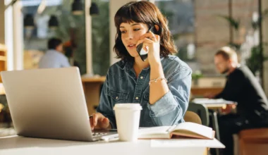Business Woman telefoniert während sie vor dem Laptop sitzt