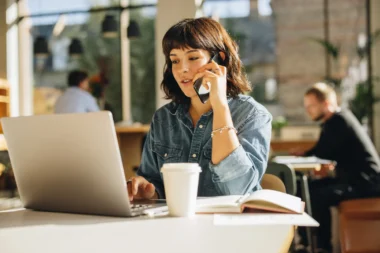 Business Woman telefoniert während sie vor dem Laptop sitzt