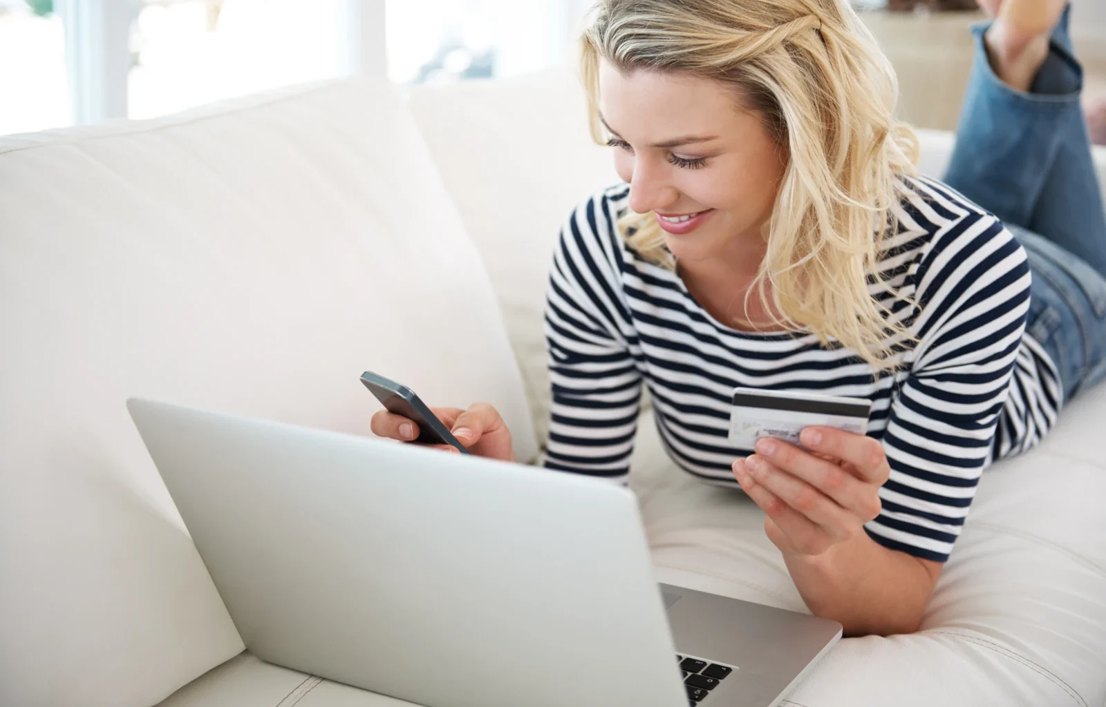junge Frau mit Kreditkarte und Smartphone beim Online-Shopping