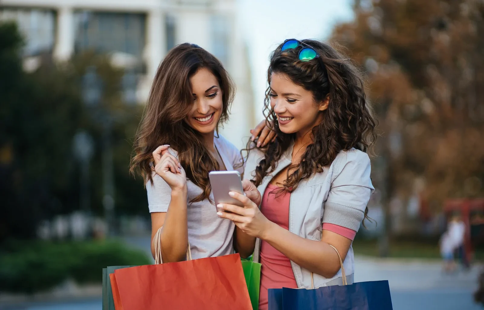 zwei junge Frauen beim Shoppen schauen auf ihr Smartphone