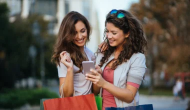 zwei junge Frauen beim Shoppen schauen auf ihr Smartphone