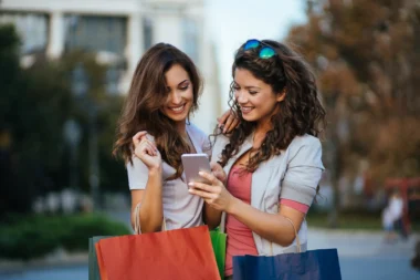 zwei junge Frauen beim Shoppen schauen auf ihr Smartphone