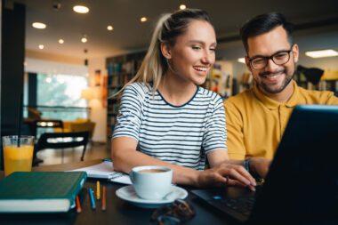 Pärchen sitzt vor einem Laptop und freut sich über die Anmeldung zu Treueprogrammen