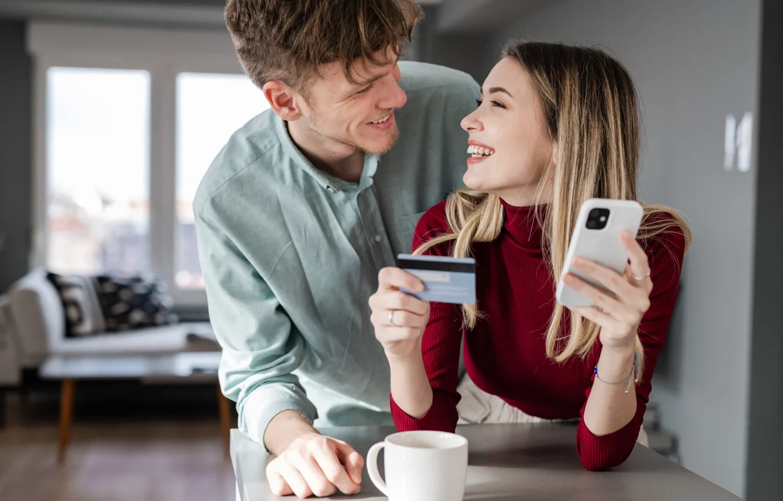 fröhliches junges Paar mit Kreditkarte beim Online-Shopping