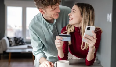 fröhliches junges Paar mit Kreditkarte beim Online-Shopping