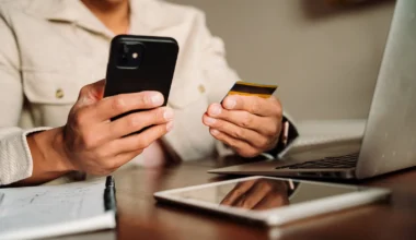 Mann hält eine Kreditkarte und sein iPhone in den Händen