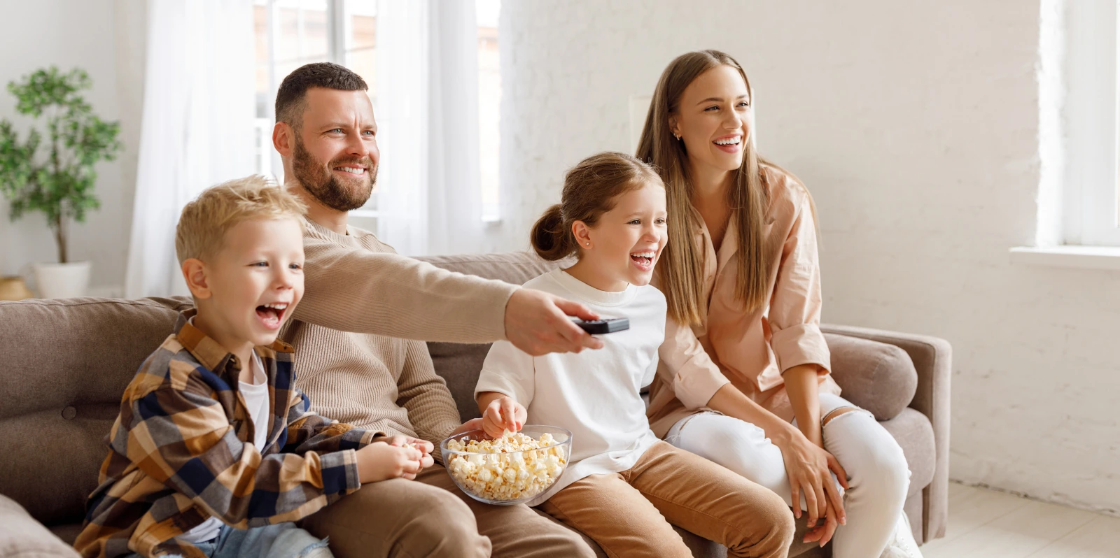fröhliche Familie schaut Zuhause TV und ißt dabei Popcorn