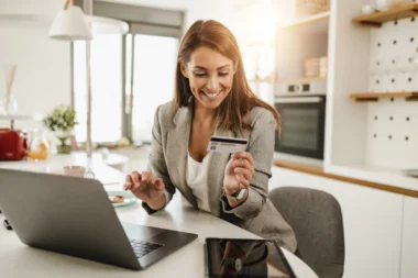 junge Geschäftsfrau am Laptop mit einer American Express Business Platinum card