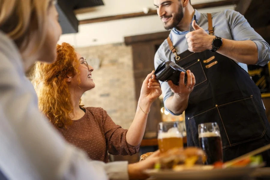 junge Frau bezahlt den Business-Lunch mit ihrer Platinum Card von American Express