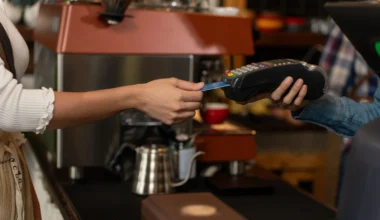 Kontaktloses Bezahlen mit Kreditkarte, Kundenfrau bezahlt Kaffee mit Kreditkarte im Café. Kleinunternehmen, Geschäftsinhaber.