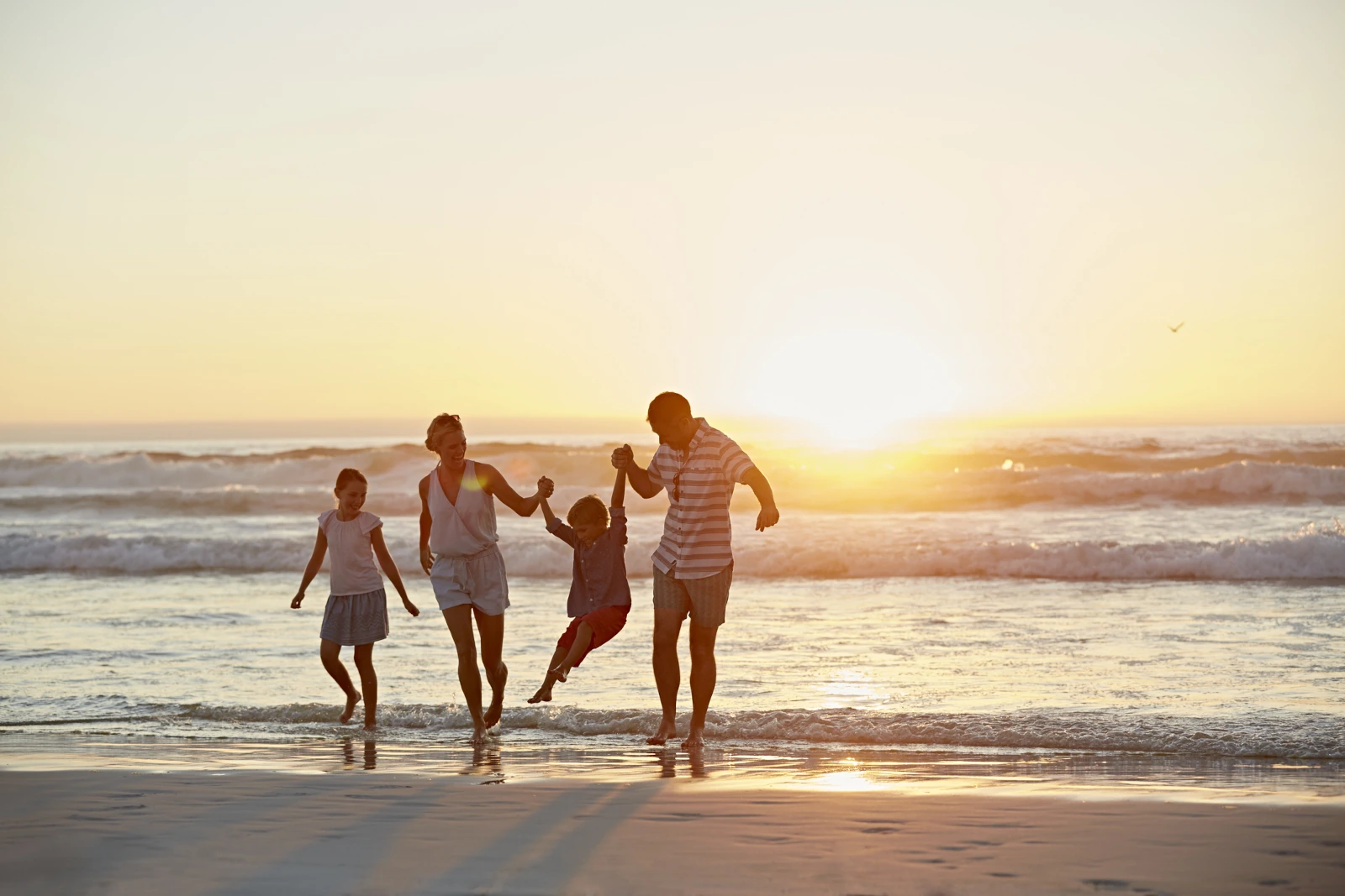 Familie mit Kindern genießt ihren Urlaub am Strand - gut abgesichert durch die Reisekrankenversicherung als Vorteile der Amex Gold Card