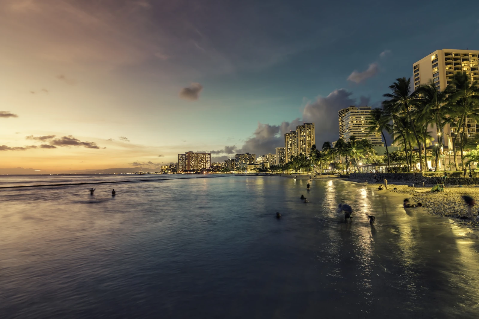 Sonnenuntergang am Waikiki Beach und Gebäude an der Küste mit Palmen in Honolulu, Hawaii