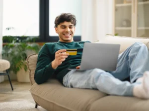 Mann mit Kreditkarte am Laptop hat die Amex Gold Card mit Willkommensbonus beantragt