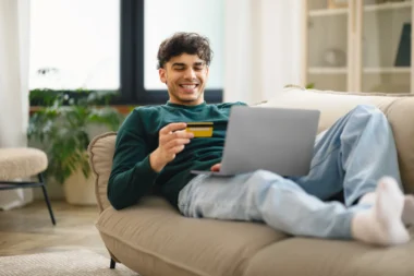 Mann mit Kreditkarte beim Online-Shopping zu Hause