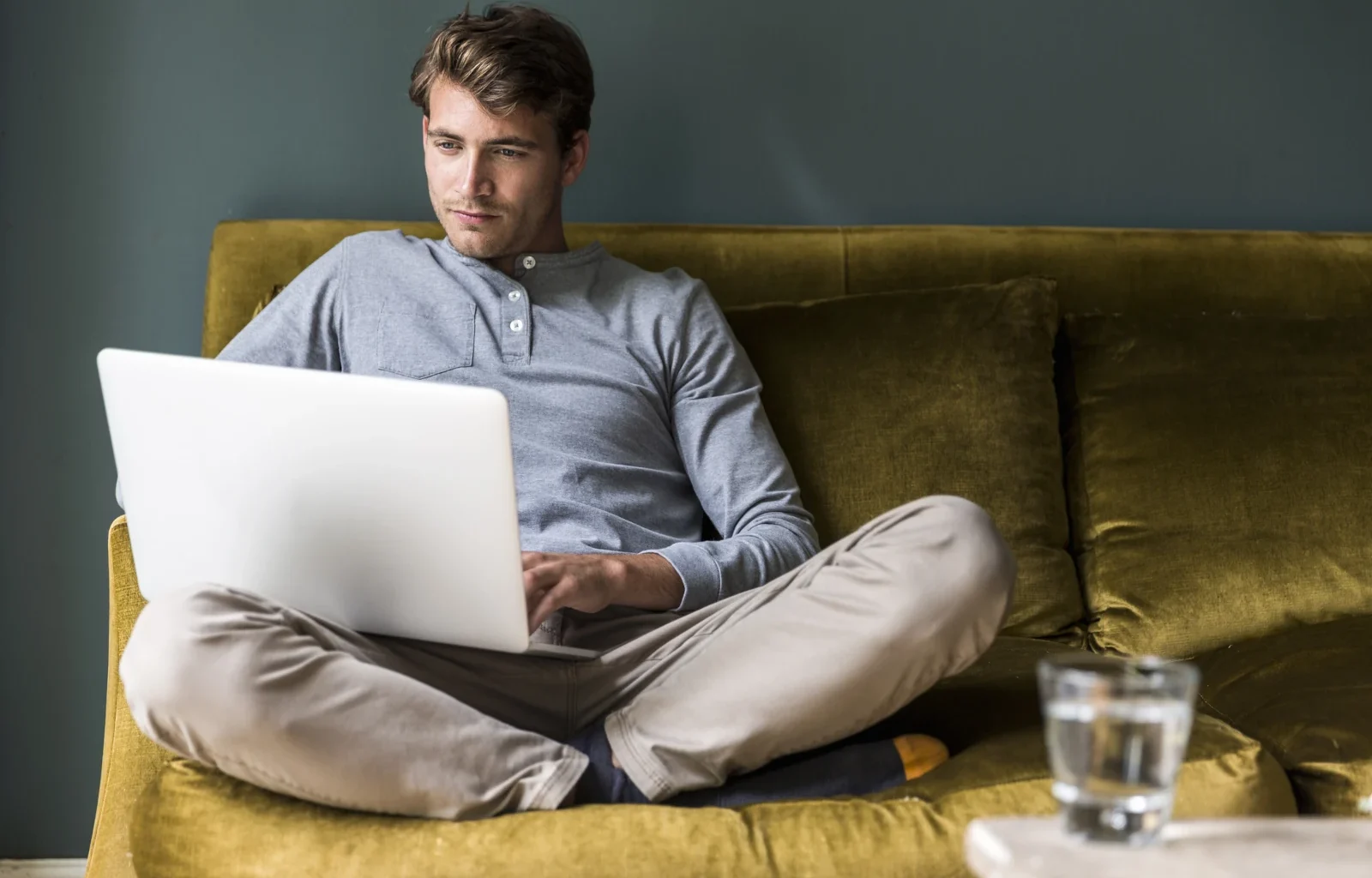Mann sitzt querbeinig, während er Laptop benutzt
