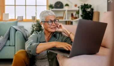 Seniorin mit Laptop auf Wohnzimmerboden