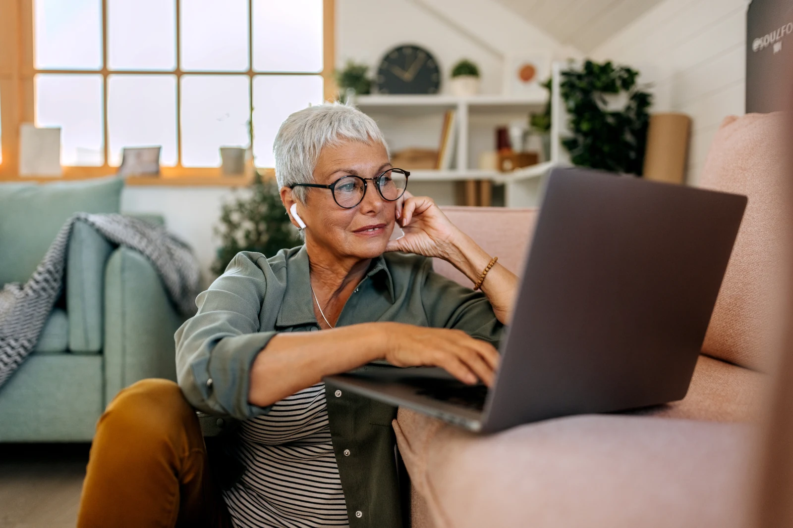 Seniorin mit Laptop auf Wohnzimmerboden