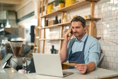 männlicher Barista macht eine Online-Bestellung mit einer Business Zusatzkarte