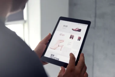 Männliche Hand stöbert in einem Online-Shop auf einem digitalen Tablet, das Schuhe verkauft