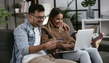 Junges Paar mit Kreditkarte und Laptop zu Hause. Freund und Freundin kaufen online