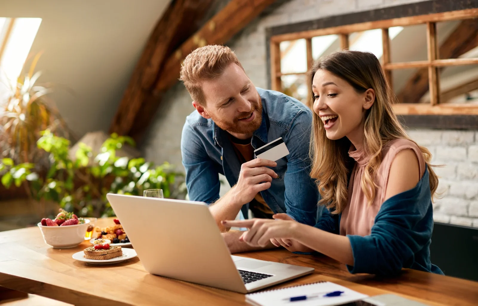 Glückliches Paar mit Spaß beim Online-Shopping zu Hause mit Kreditkarte