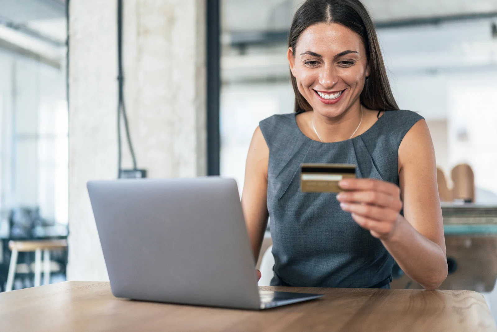 junge Frau im Büro am Laptop bei einer Online-Bestellung mit Kreditkarte