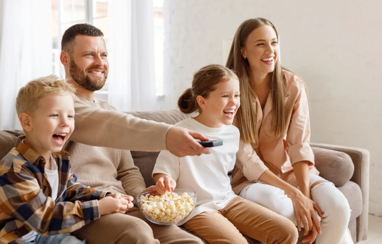 fröhliche Familie schaut Zuhause TV und ißt dabei Popcorn mit dem Amex Platinum Entertainmentgutgaben