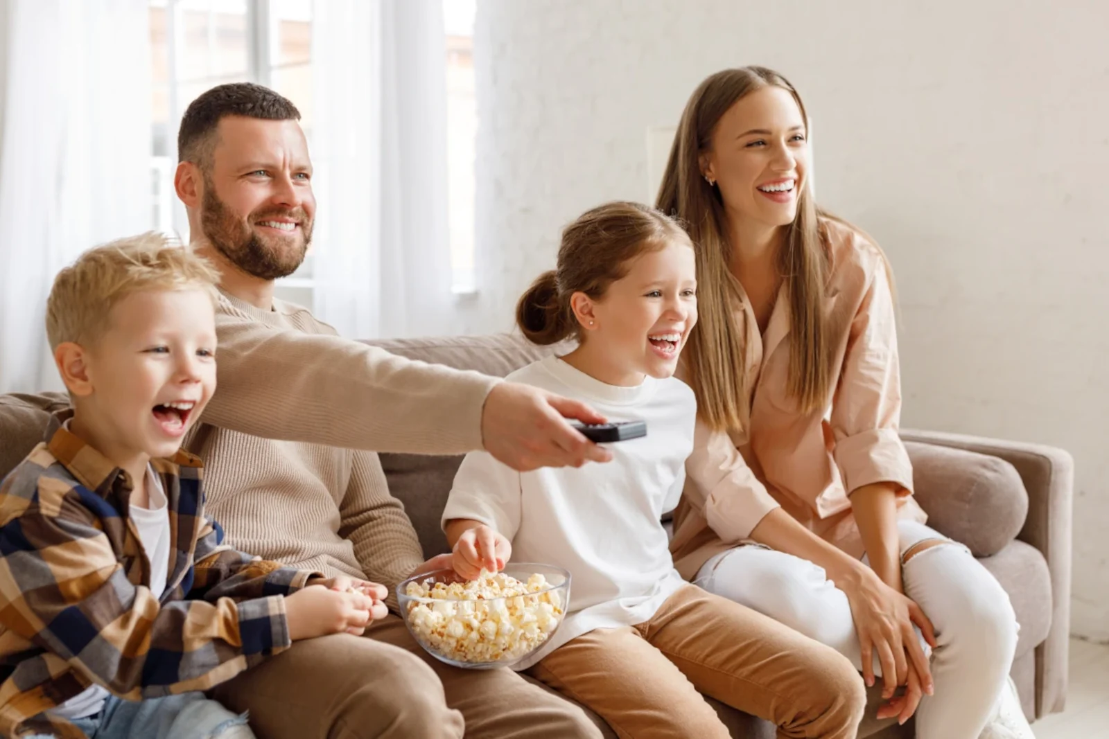 fröhliche Familie schaut Zuhause TV und ißt dabei Popcorn mit dem Amex Platinum Entertainmentgutgaben