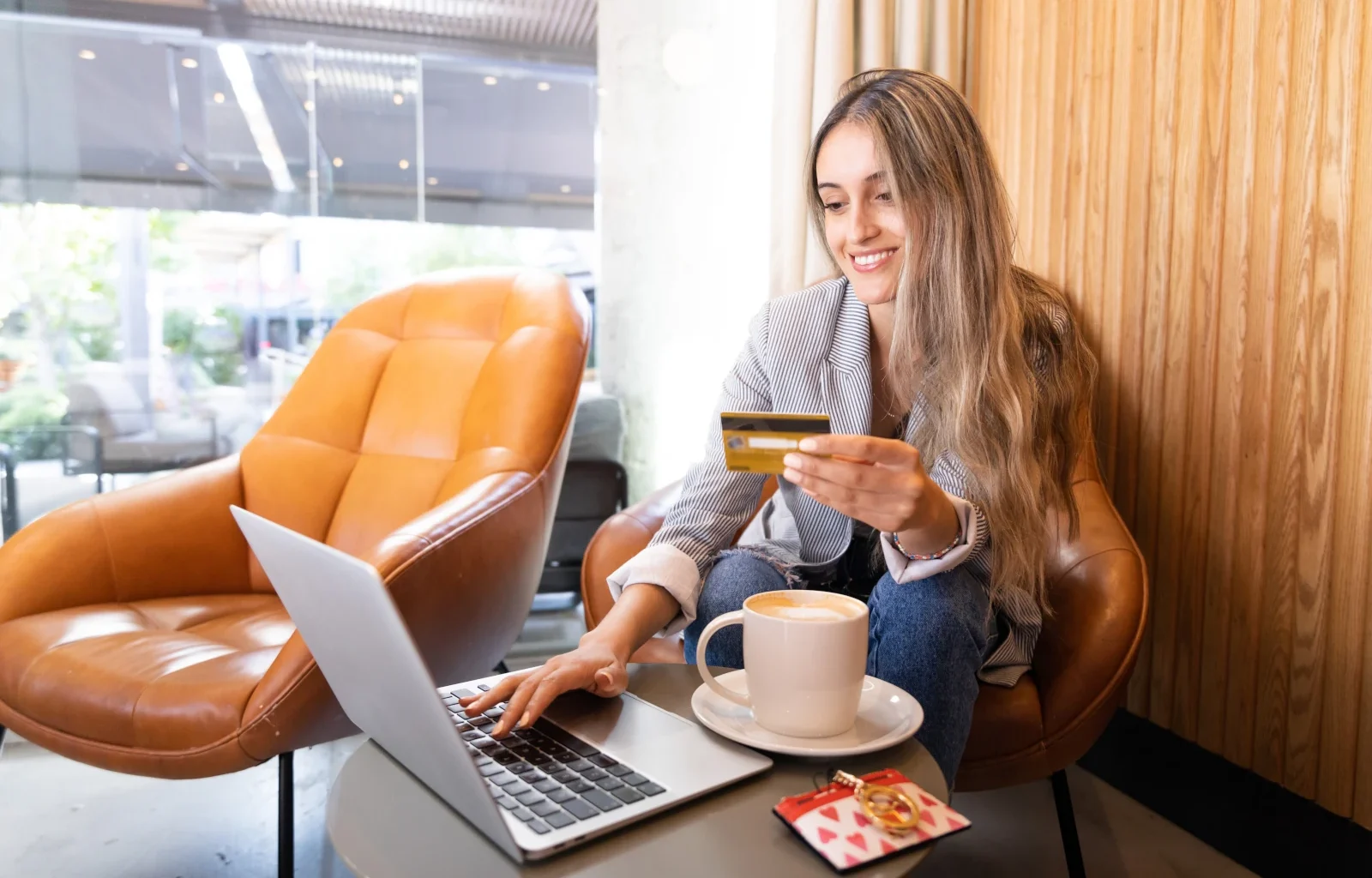 Lächelnde junge Frau, die mit Business Kreditkarte in einem Café mit Kreditkarte eine Reise bucht