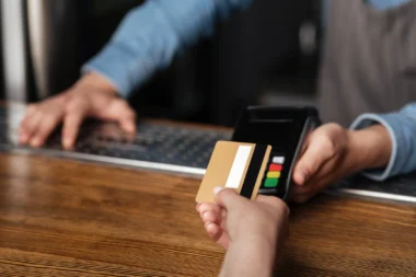 junge Frau nutzt Kreditkarte zum Bezahlen, Barkeeper hält Terminal über den Tresen