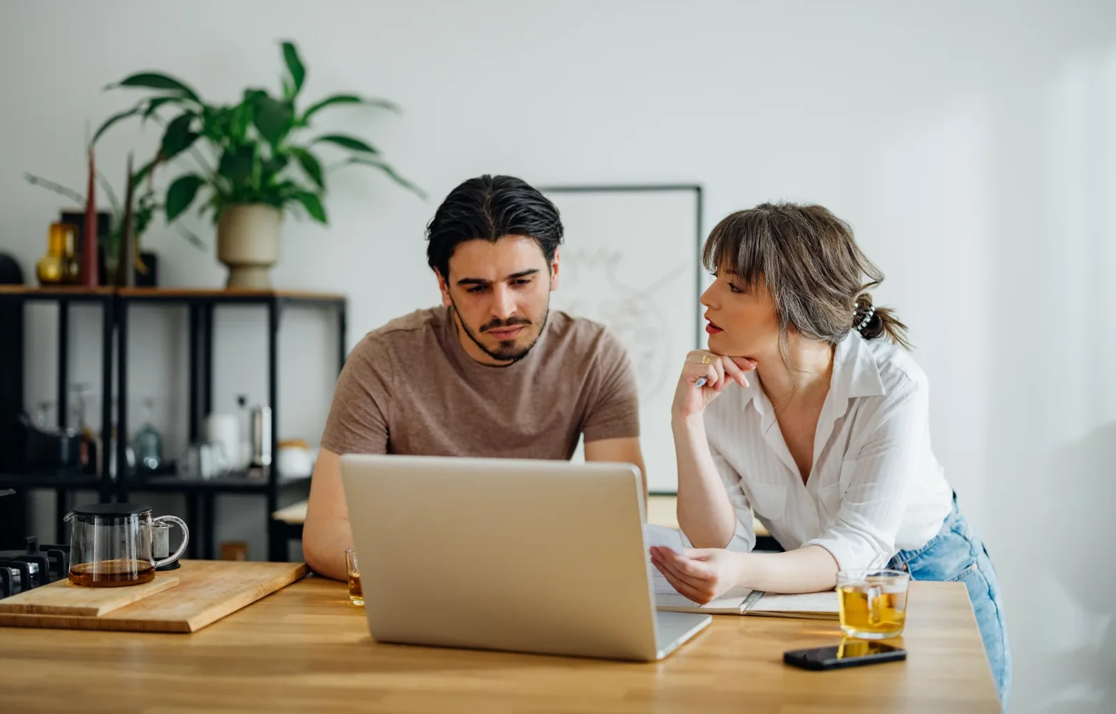 Paar erledigt gemeinsam Haushaltsfinanzen online auf einem Laptop in der Küche.