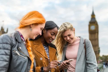 Gruppe von Mädchen in London neben Big Ben Städtereise überprüfen Karte auf dem Smartphone