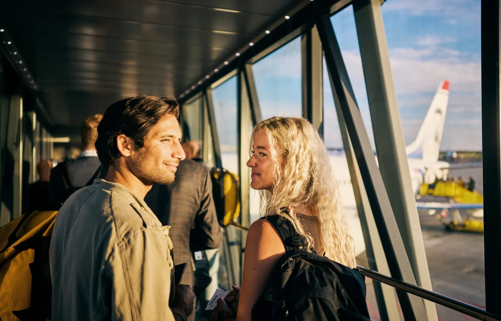 Junges Paar, das in einen Wochenendurlaub geht und das Flugzeug besteigt - mit ihrem 200 Euro Reiseguthaben der Amex Platinum Card gebucht