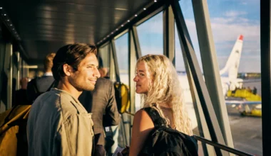 Junges Paar, das in einen Wochenendurlaub geht und das Flugzeug besteigt - mit ihrem 200 Euro Reiseguthaben der Amex Platinum Card gebucht