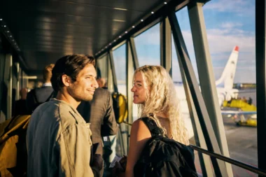 Junges Paar, das in einen Wochenendurlaub geht und das Flugzeug besteigt - mit ihrem 200 Euro Reiseguthaben der Amex Platinum Card gebucht